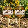 Xerces yard signs in front of a home garden, with fallen leaves on the ground. One reads "Leave the Leaves", while the second, in Spanish, reads "Las Hojas son Vitales".