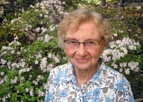 A smiling woman in front of a blooming bush