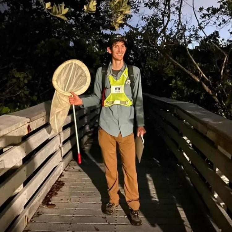 Richard Joyce holds a bug net on a bridge at dusk